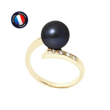 Le Perlinea Bague LYSANDRA en or jaune est orné d'une grande perle de culture Black Tahiti et d'une rangée de petits diamants sur l'anneau, affichés sur fond blanc avec le logo de l'Artisan Bijoutier Français dans le coin supérieur gauche.
