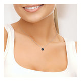 Une femme porte un haut blanc sans manches et le collier Perlinea Collier 2C - un collier en argent 925 avec un pendentif en perle de culture noire de Tahiti. Elle sourit, seuls le bas du visage et le cou sont visibles.