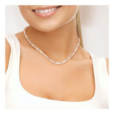 Une femme vêtue d'un haut blanc sans manches sourit, mettant en valeur le collier Collier NOELYSE de Perlinea, un collier artisanal français en argent avec des perles multicolores de 5/6 mm, qui orne élégamment son cou.