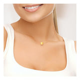 Une femme vêtue d'un haut blanc sourit, montrant un gros plan de son cou et de ses épaules. Elle porte le collier Perlinea SOFIA | Perle Dorée, orné d'une seule perle ronde dorée.