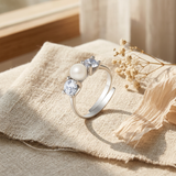 Bague ouverte en argent 925 avec perle de culture blanche et deux zircons sertis.