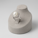Bague en argent 925 ornée d'une perle de culture blanche entourée de zircons, sur présentoir.