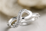 Bague infini ajustable en argent 925 ornée de cristaux pavés sur fond neutre.