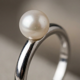 Gros plan sur la perle de culture blanche sertie sur la bague jonc en argent 925.