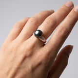 Bague en or blanc 9 carats ornée d'une perle de Tahiti noire portée à l'annulaire.