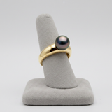 Bague en or jaune 9 carats sertie d'une perle de Tahiti noire aux reflets irisés.