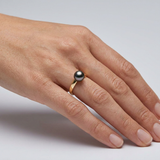 Bague en or jaune 9 carats portée à l'index, ornée d'une perle de Tahiti noire 8/9mm.