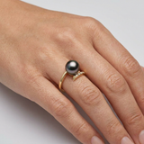 Bague or jaune 9 carats portée à l'index, perle de Tahiti noire et diamants sur anneau ouvert.