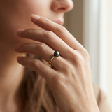 Bague or jaune 9 carats à perle noire de Tahiti et diamants portée à l'index.