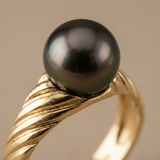 Bague or jaune sertie d'une perle de Tahiti noire aux reflets irisés, anneau torsadé.