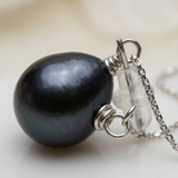 Gros plan sur une perle de culture noire de Tahiti montée sur chaîne en or blanc 9 carats.