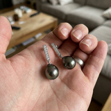 Boucles d'oreilles argent 925 avec perles noires de Tahiti tenues dans une paume.