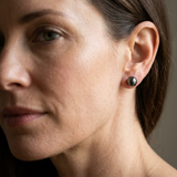 Boucles d'oreilles bouton en argent 925 avec perle de Tahiti noire, portées à l'oreille.