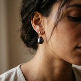 Boucles d'oreilles en or jaune 9 carats avec perle de culture noire de Tahiti portées à l'oreille.