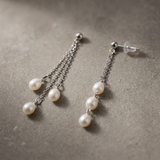 Boucles d'oreilles pendantes or blanc 9 carats avec trois perles de culture blanches en cascade.