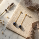 Boucles d'oreilles pendantes or jaune 9 carats avec perles noires de Tahiti sur chaîne fine.
