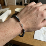 Bracelet en argent 925 et perles noires 6/7 mm avec fermoir mousqueton, porté au poignet.