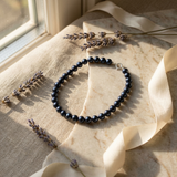 Bracelet en argent 925 et perles noires disposé sur marbre, avec fermoir anneau argenté.