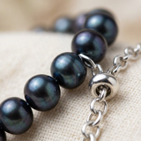 Gros plan sur le fermoir réglable en argent 925 d'un bracelet à perles noires 6/7 mm.