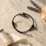 Bracelet homme en coton ciré noir avec perle de Tahiti grise 10/11mm, présentation à plat.