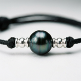 Gros plan sur la perle de Tahiti 10/11mm d'un bracelet homme en coton ciré noir avec perles argent.