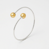 Bracelet jonc ouvert en argent 925 avec deux perles dorées aux extrémités.