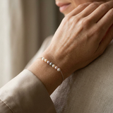 Bracelet en or blanc 9 carats avec perles multicolores porté au poignet.