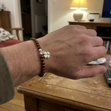Bracelet perles d'eau douce chocolat et argent 925 avec charm trèfle, porté au poignet.