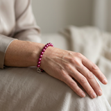 Bracelet en perles d'eau douce rouge cerise avec fermoir argent 925, porté au poignet.