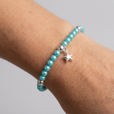 Bracelet perles d'eau douce bleu turquoise et argent 925 avec charm étoile, porté au poignet.