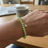 Bracelet perles d'eau douce vertes et argent 925 avec charm étoile, porté au poignet.