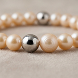 Gros plan sur les perles d'eau douce roses et billes en argent 925 d'un bracelet porte bonheur.
