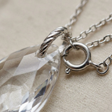 Gros plan sur le fermoir anneau et la bélière torsadée en argent 925 d'un collier à pendentif cristal facetté.