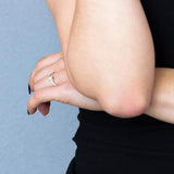Bague solitaire en argent 925 ornée d'un oxyde de zirconium blanc serti 4 griffes, portée à la main.