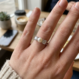 Bague en argent 925 ornée d'une perle de culture blanche, portée à l'annulaire.