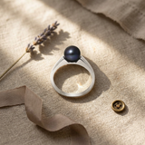 Bague en argent 925 sertie d'une perle de culture noire de Tahiti, posée sur lin.