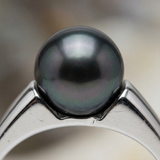 Gros plan sur la perle de Tahiti noire d'une bague en argent 925, reflets irisés.