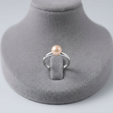 Bague jonc argent 925 sertie d'une perle de culture rose, présentée sur un support gris.