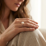 Bague en or blanc 9 carats avec perle blanche portée à l'annulaire.