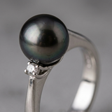 Gros plan sur la perle de Tahiti noire irisée et le diamant serti en or blanc 9 carats.