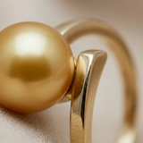 Gros plan sur la perle dorée et le sertissage en or jaune 9 carats de la bague Elise.