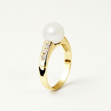 Bague or jaune 9 carats avec perle de culture blanche et diamants sur fond neutre.