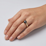 Bague or jaune 9 carats portée à l'annulaire, perle noire de Tahiti et diamants.