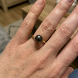 Bague en or jaune 9 carats ornée d'une perle de culture noire de Tahiti, portée à l'annulaire.