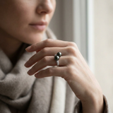 Bague toi & moi en argent 925 avec deux perles de Tahiti noires et oxyde de zirconium, portée à la main.