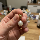 Boucle d'oreille or blanc 9 carats avec perle de culture blanche baroque en main.