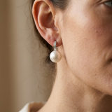 Boucles d'oreilles en argent 925 avec perle blanche portées à l'oreille.
