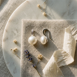 Boucles d'oreilles en argent 925 avec perles blanches rondes, présentées sur lin beige.