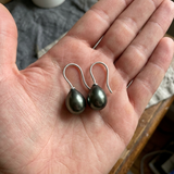 Boucles d'oreilles en argent 925 avec perles de Tahiti grises en forme de goutte, tenues dans une paume.
