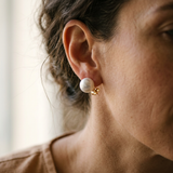 Boucles d'oreilles bouton en or jaune 9 carats avec perle de culture blanche, portées à l'oreille.